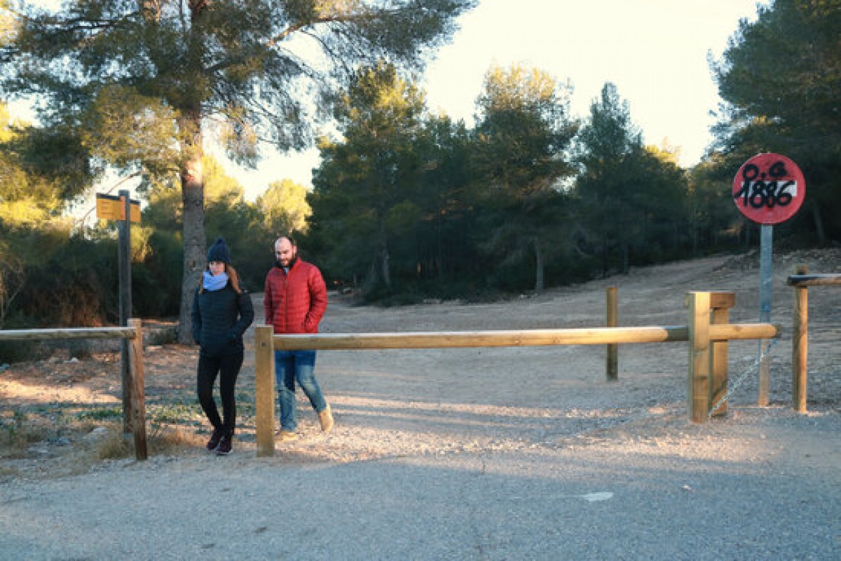 Una parella al seu pas per la tanca col·locada en un dels accessos del Parc Ecohistòric del Pont del Diable que evita el trànsit rodat