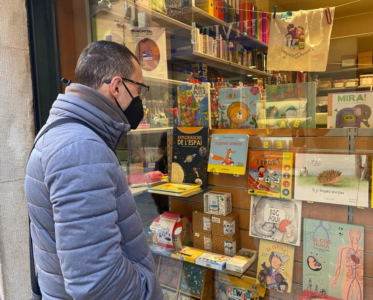 Un home amb mascareta es mira l'aparador d'una llibreria, dies enrere, a Reus