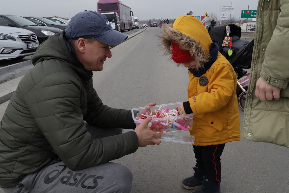 Un home ofereix caramels a un nen després de passar la frontera cap a Polònia
