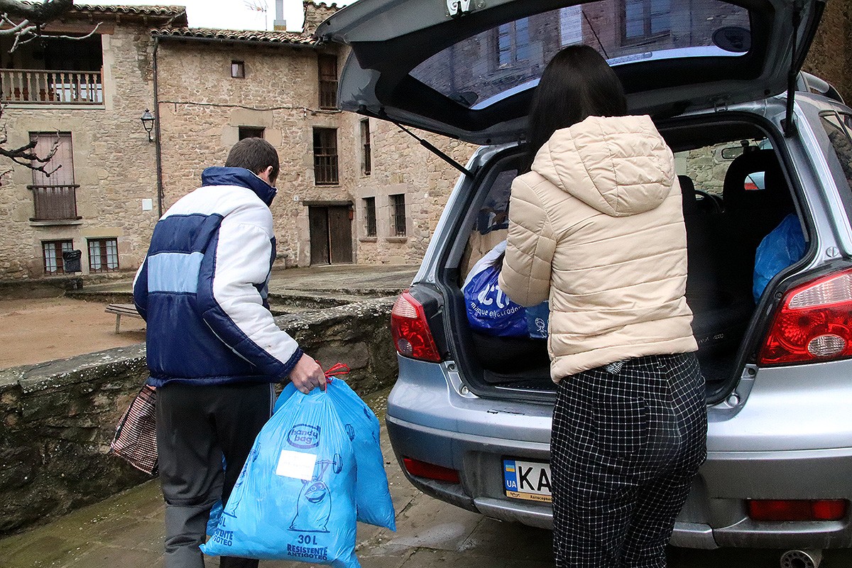 Dues persones refugiades d'Ucraïna que viuen a Osona treuen bosses del cotxe.