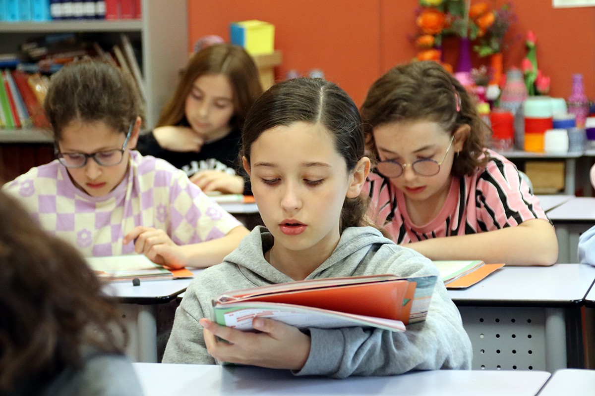 Una alumna de cinquè de primària llegeix a classe en veu alta sense mascareta.