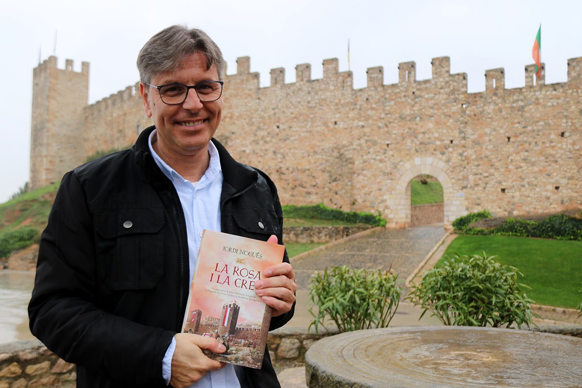 L'escriptor Jordi Nogués subjectant la seva nova novel·la La rosa i la creu davant les muralles de Montblanc.