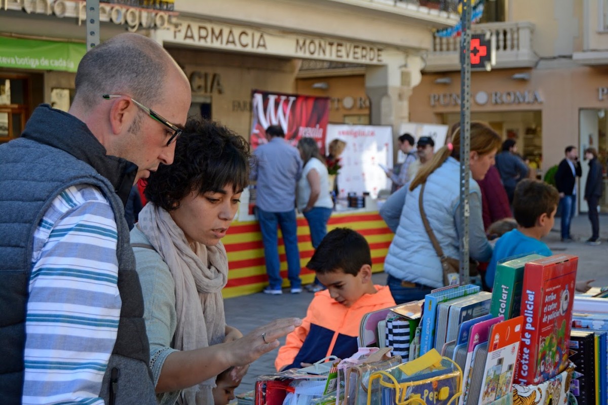 Una família es mira llibres d'una parada, en una anterior celebració de Sant Jordi a Reus