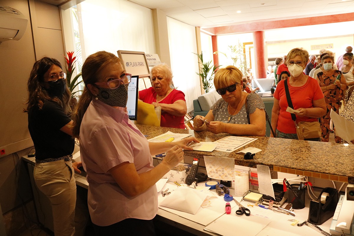 Treballadores a la recepció d'un hotel de Salou, atenent llargues cues de clients per registrar-se.