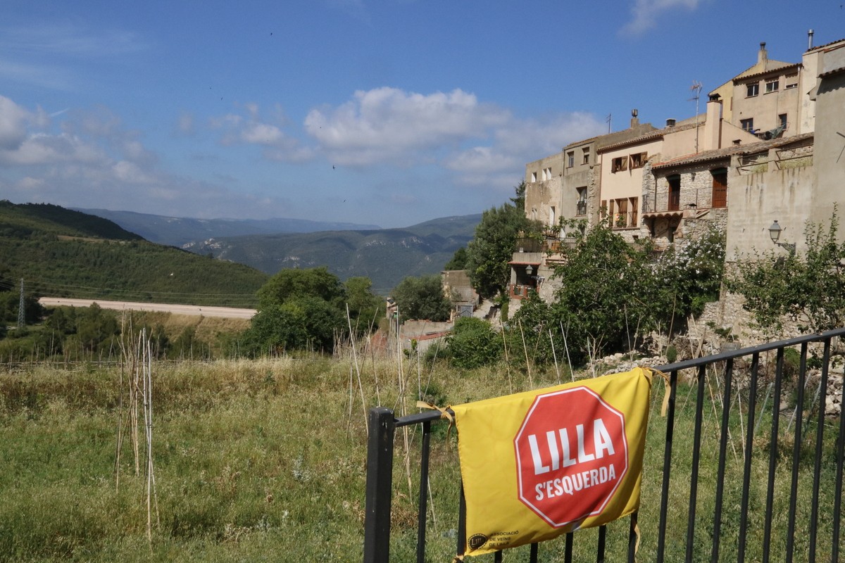 Un cartell denunciant que Lilla s'esquerda, en un punt panoràmic d'aquest poble de la Conca de Barberà afectat per esquerdes, amb les obres de l'autovia A-27 al fons