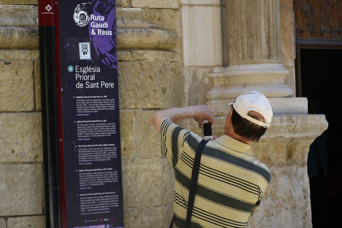 Un turista fotografia un plafó informatiu de la Prioral de Sant Pere, de Reus