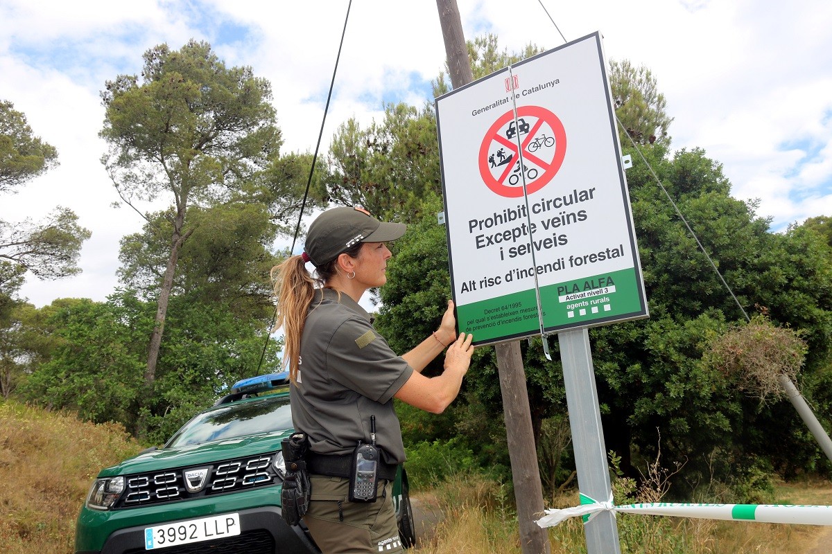 Una agent rural desplega un cartell que informa sobre el tancament del parc natural del Montgrí