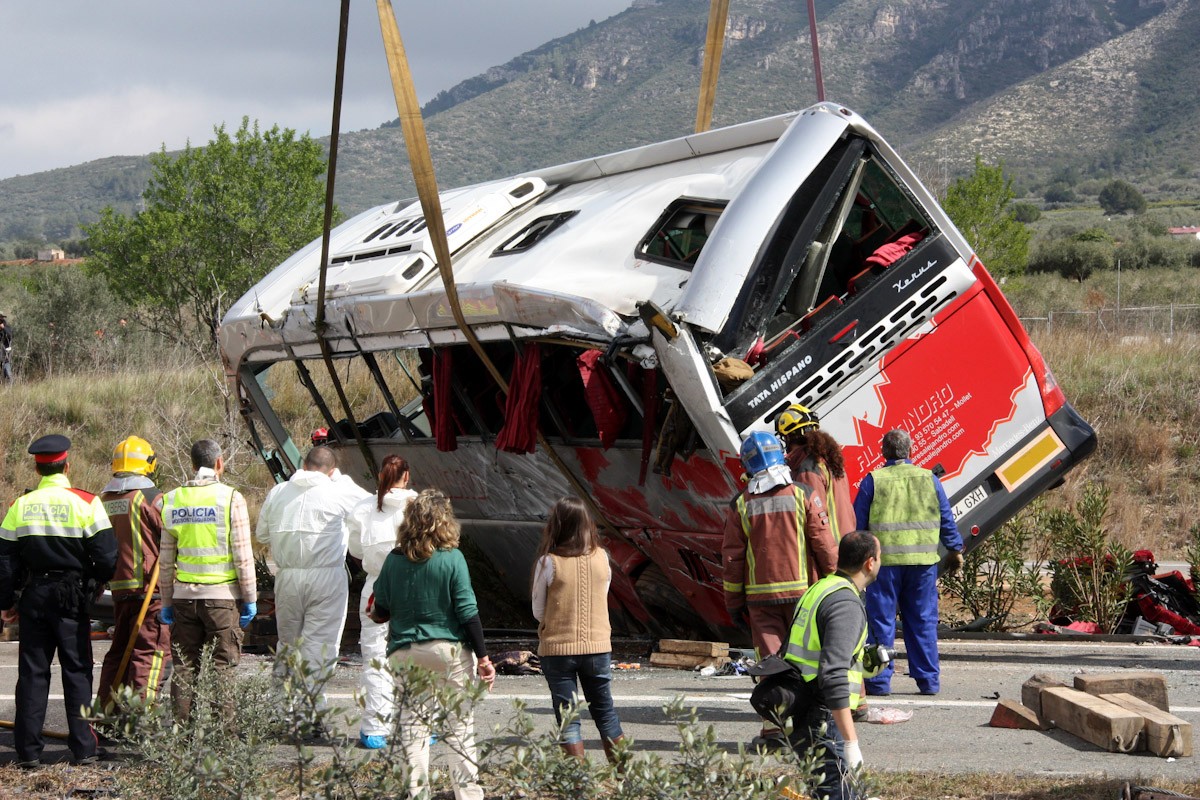 Efectius mirant com la grua està aixecant l'autobús accidentat a l'AP-7 a Freginals, aquest 20 de març de 2016. 