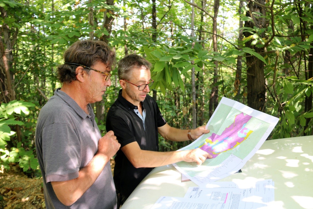 Carlos Corominas i Joan Rovira mirant el mapa de la superfície forestal i l'àrea on no es permet fer un canvi d'espècie 
