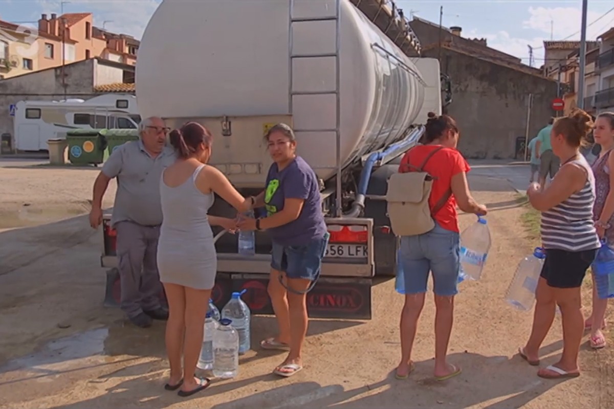 Veïns i veïnes de La Batllòria emplenant garrafes d'aigua d'un camió cisterna