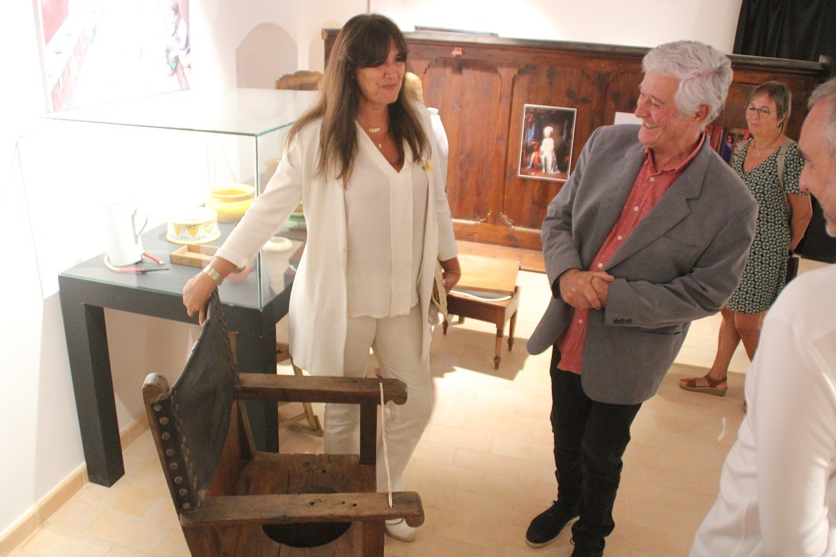 El comissari de l'exposició, Màrius Codina, mostra a Laura Borràs una curiosa cadira per fer les necessitats