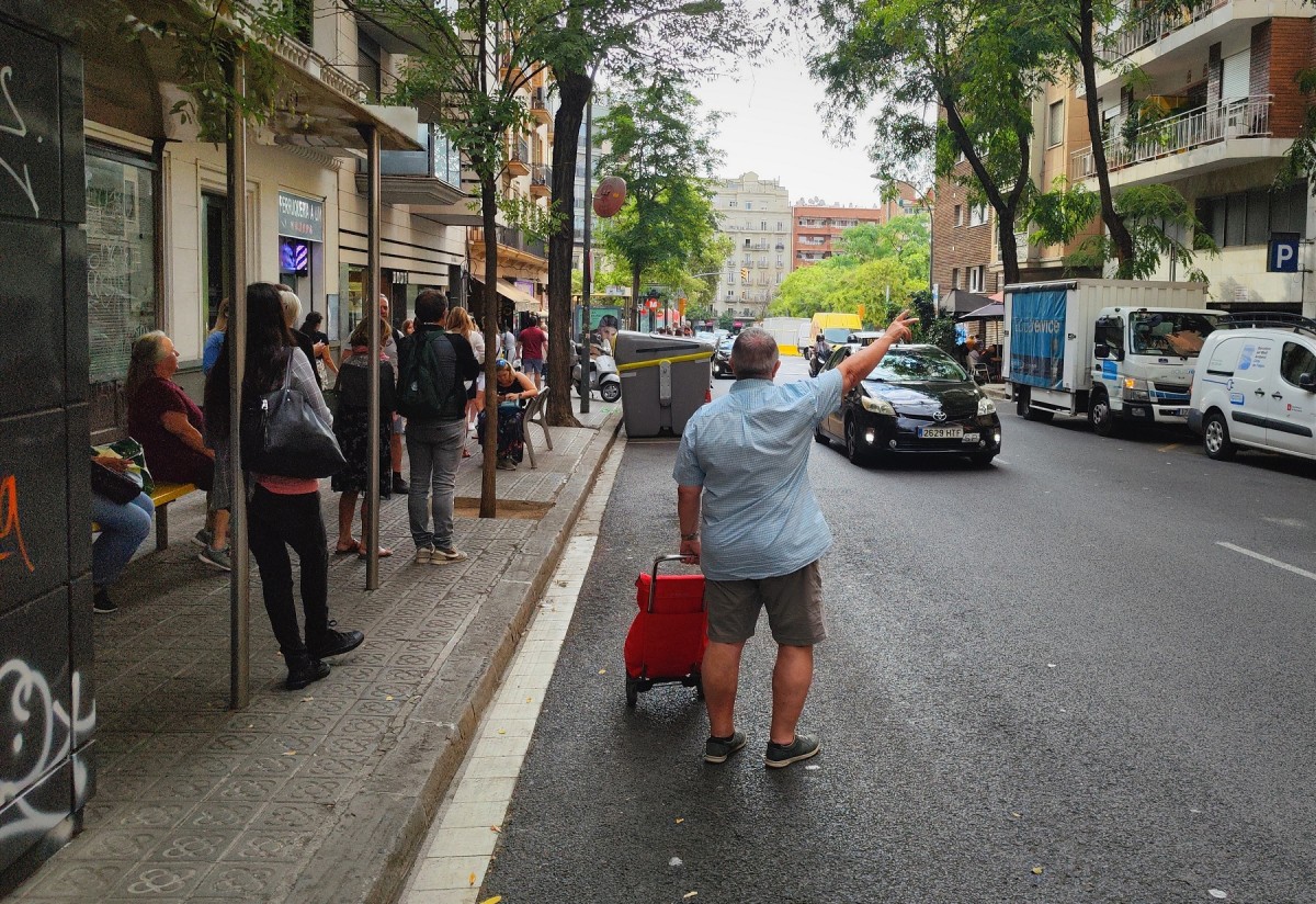 Un home amb un carret de la compra demana un taxi, per la vaga d'autobusos