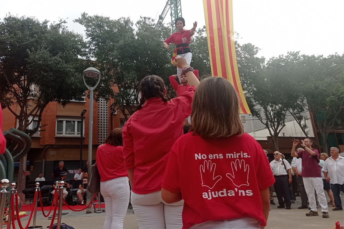 Una castellera llueix una samarreta amb el lema «No ens miris, ajuda'ns»