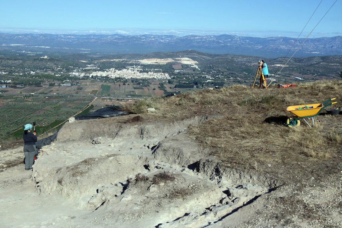 Vista general dels treballs dels arqueòlegs del GRAP de la UB al poblat de la Cogula, amb el nucli urbà d'Ulldecona, al fons  