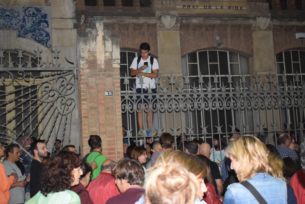 Un jove enfilat a la tanca del col·legi Prat de la Riba, de Reus, quan es van tancar les votacions del referèndum