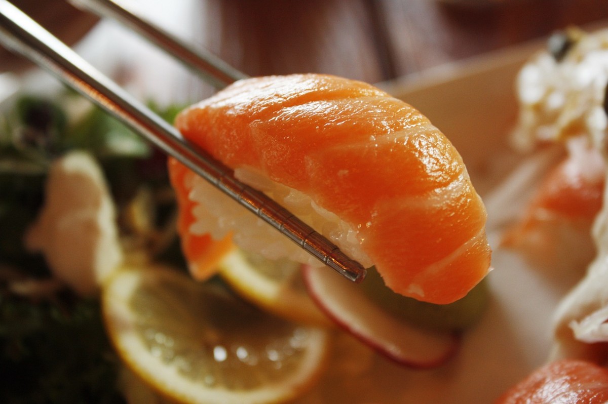 Una persona utilitza bastonets per menjar sushi de salmó