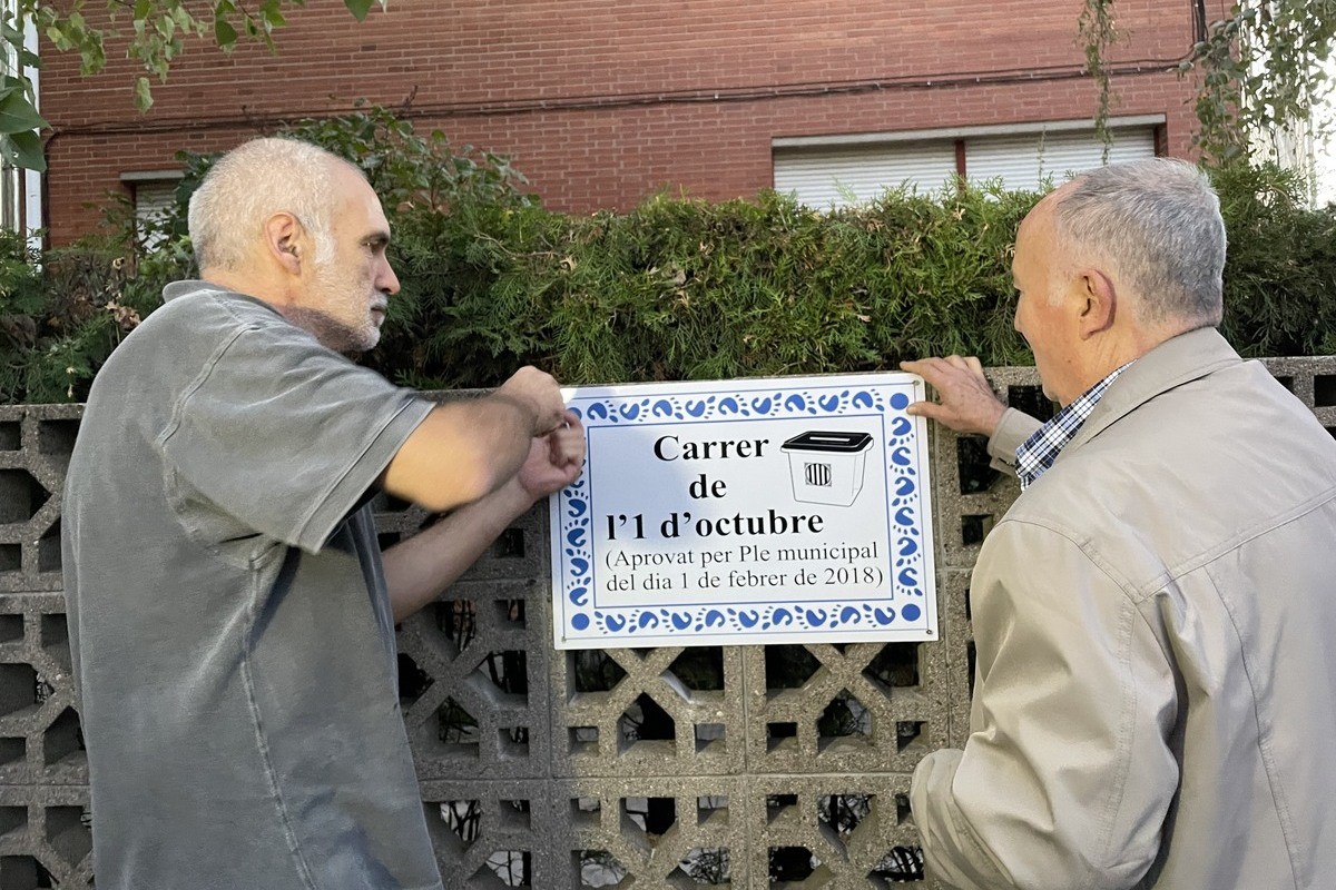 Dos manifestants col·locant la nova placa davant la caserna