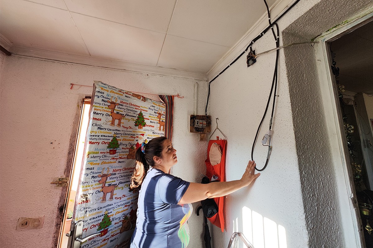 Alba Gómez, veïna sense llum regularitzada, mostrant la instal·lació de casa seva.
