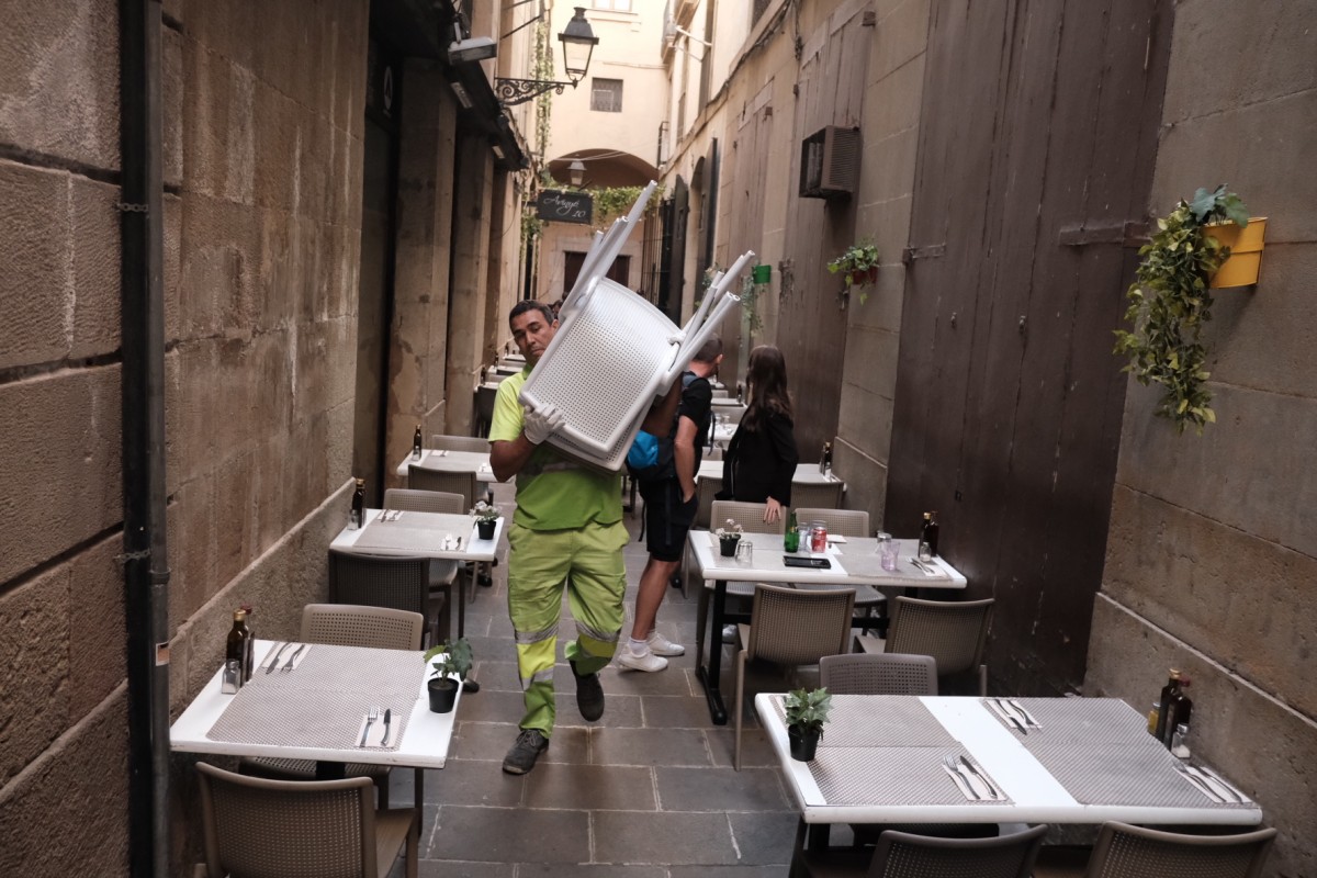 Un operari de l'Ajuntament carregant taules de la terrassa desmantellada al Gòtic