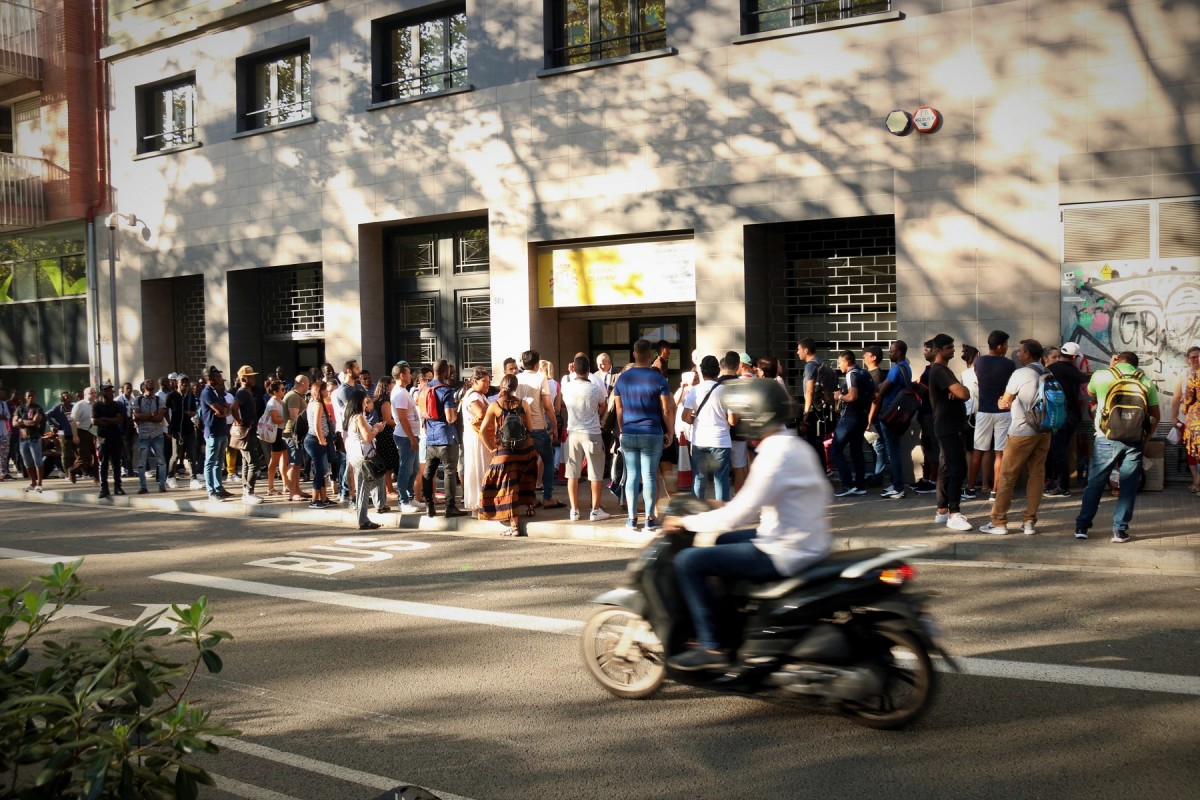 Cua de persones migrades esperant un tràmit a una oficina d'estrangeria del govern espanyol a Barcelona