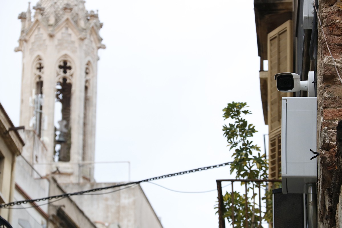 Pla detall d'una càmera de videovigilància instal·lada al carrer de la Cort de Valls, amb el campanar de Sant Joan al fons.