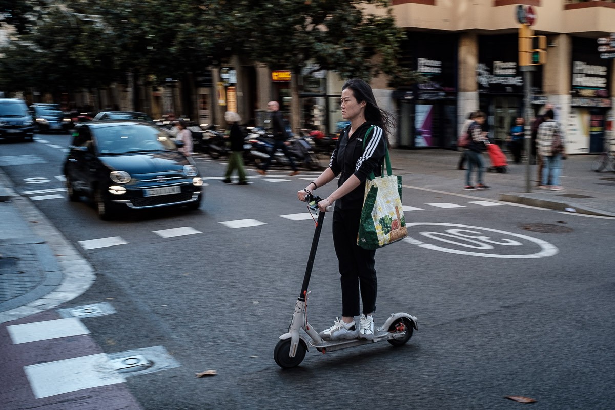 Una noia circulant amb patinet elèctric pel barri de Gràcia.