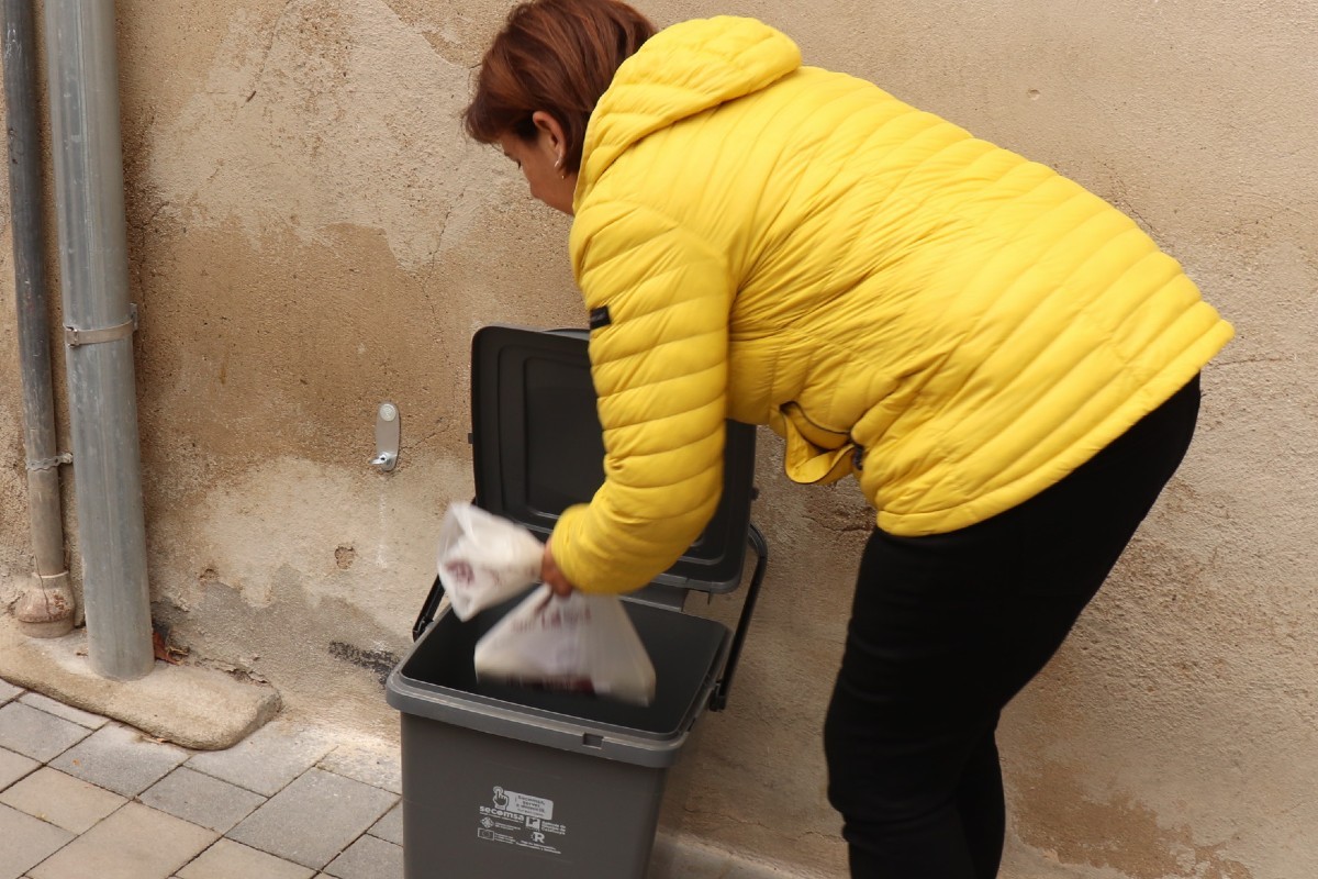Una veïna de Castellvell del Camp dipositant una bossa de compostatge en un dels cubells del «Porta a Porta»