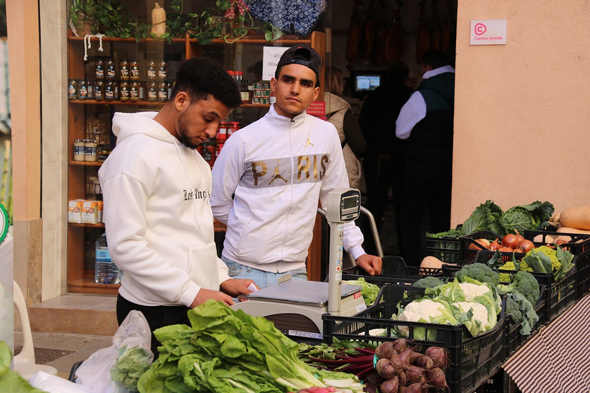 Joves extutelats al mercat de Valls venent verdures que han conreat ells mateixos en una finca del municipi.