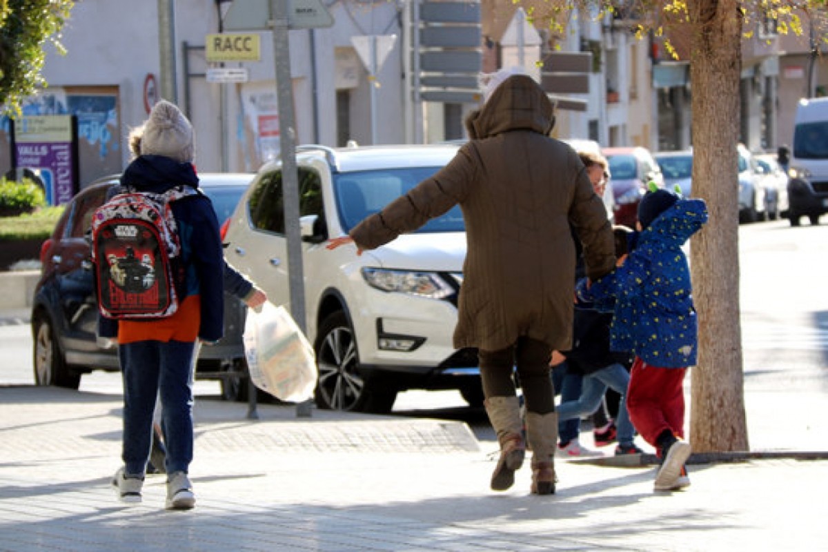 Imatge d'arxiu d'una família caminant enmig del vent en una població catalana
