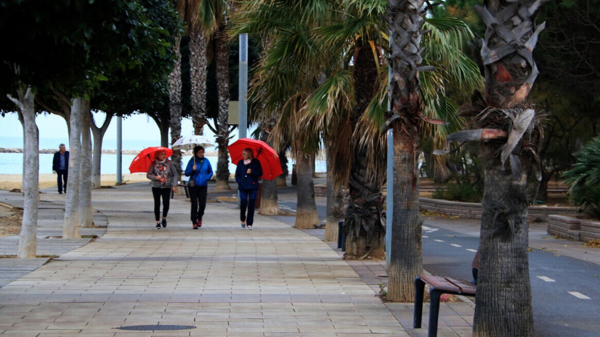 Tres dones passegen amb paraigües pel passeig marítim de Cambrils, l'últim dia del pont de desembre
