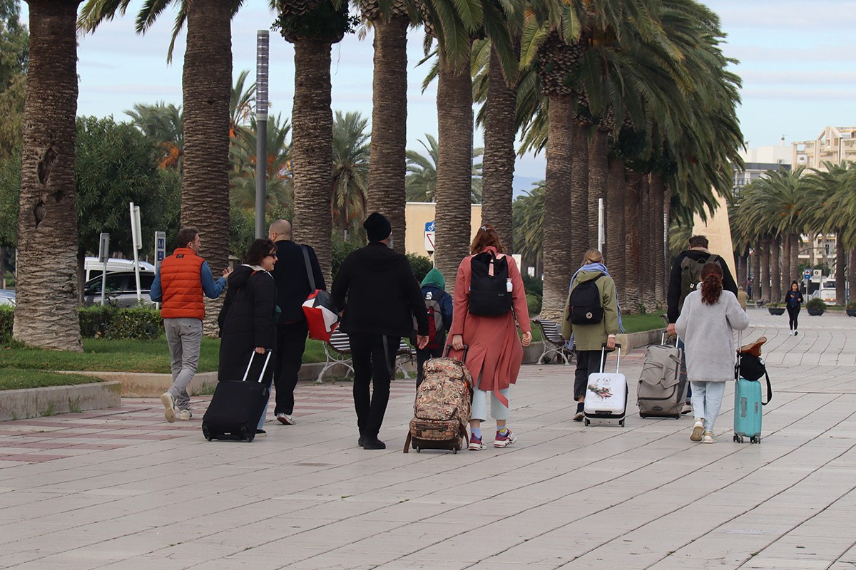 Un grup de persones amb maletes caminant pel passeig Jaume I de Salou.
