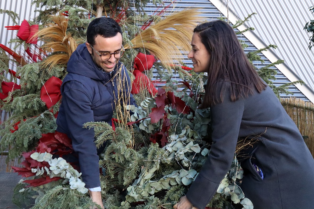 Dues persones col·locant el seu arbre de Nadal en la zona habilitada al Parc Central de Tarragona en el marc de la campanya Dona una segona vida al teu arbre.
