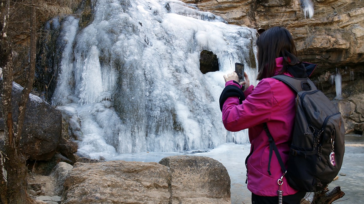 Una visitant fotografiant una de les cascades glaçades durant aquests dies d'hivern