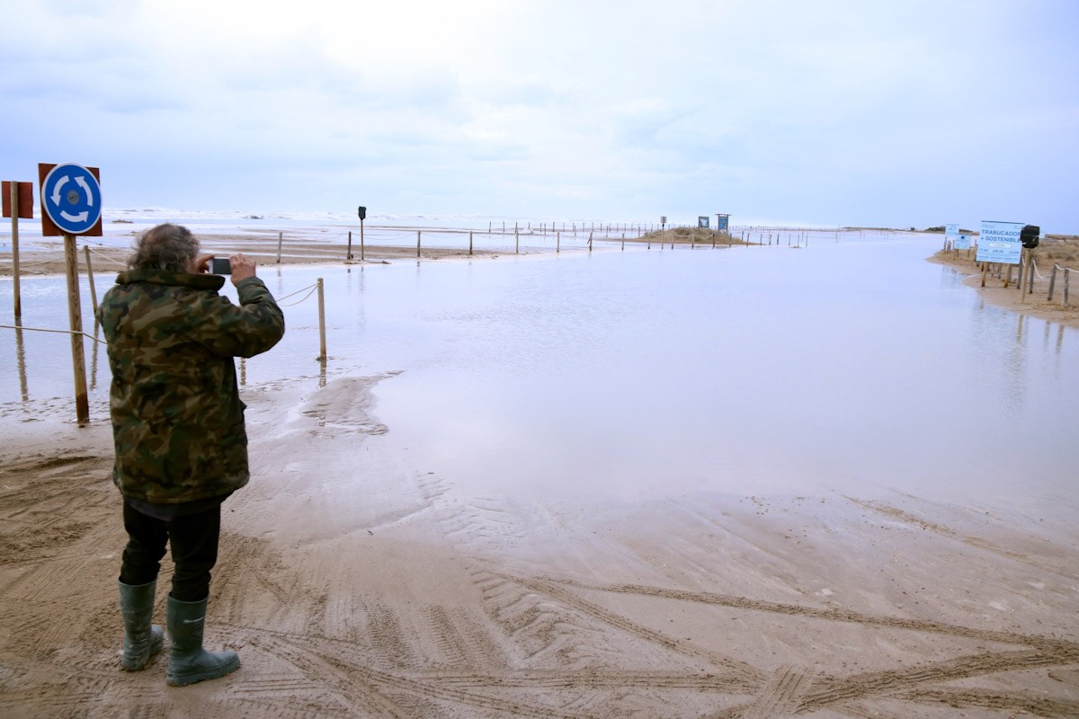 Un home prenent imatges de l'accés a la barra del Trabucador inundat pel mar  
