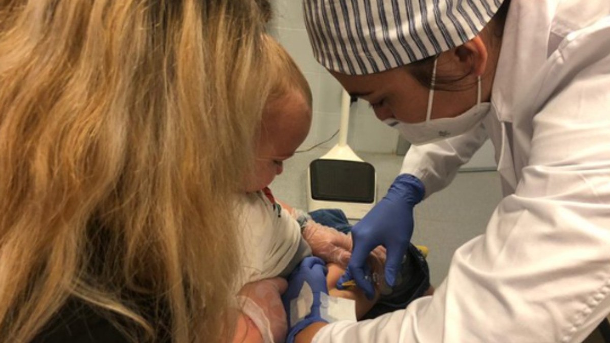 Un pediatra vacuna un nadó.