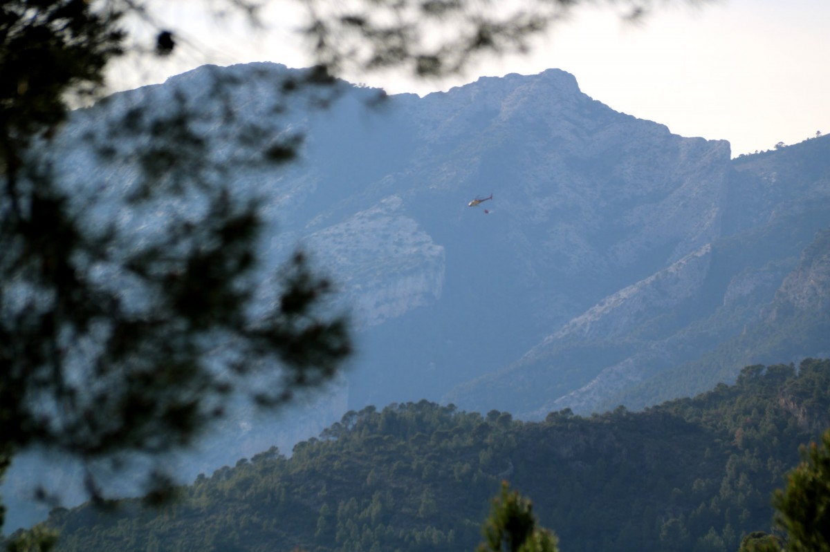 Un helicòpter dels Bombers passa per sobre de les muntanyes de Paüls durant l'extinció de l'incendi  