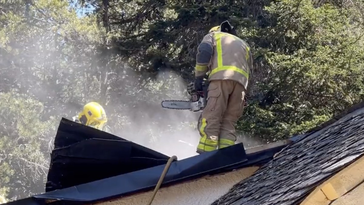 Dos efectius dels Bombers sanejant un teulat afectat pel foc en una imatge d'arxiu
