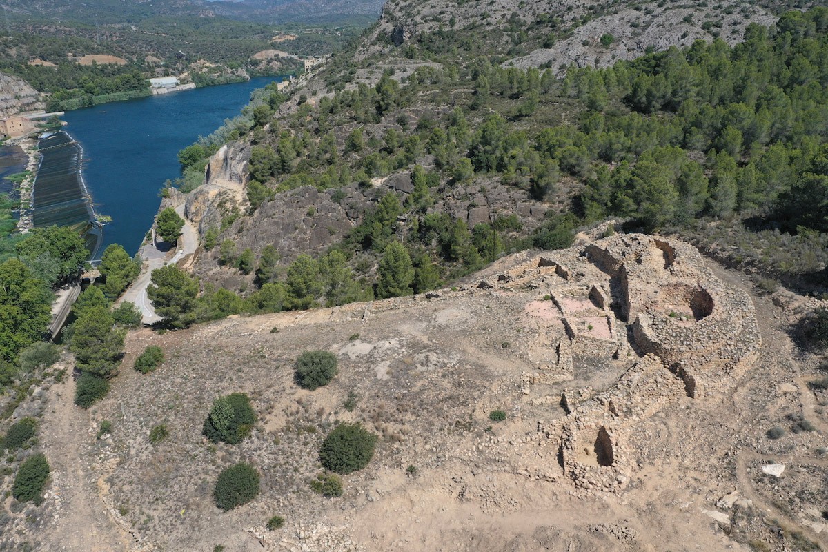 Imatge aèria del jaciment ibèric de l'Assut de Tivenys, amb l'estructura defensiva que corona el poblat, a la dreta, i el riu Ebre al fons V