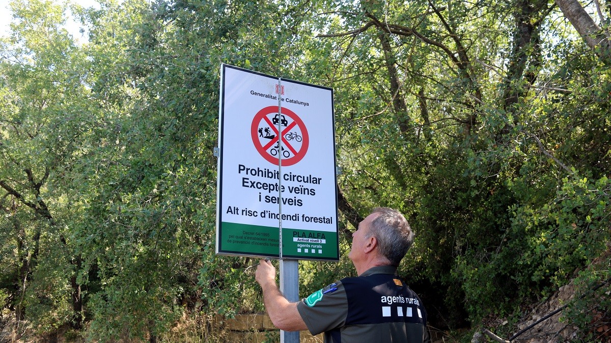Un agent rural obrint un cartell que prohibeix el pas al Montsec