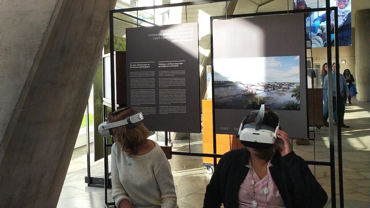 Dues dones provant les ulleres de realitat virtual a l'estand del Geoparc