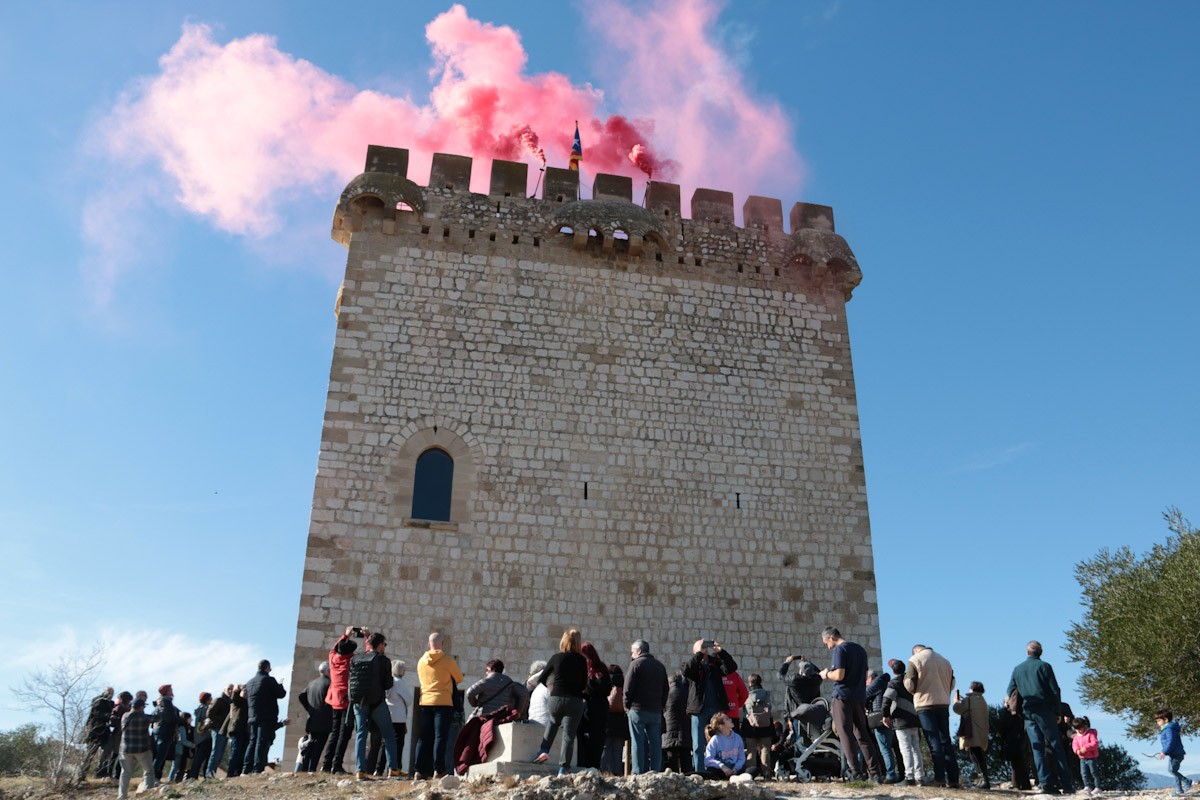 Una trentena de persones observant i fotografiant l'encesa de la Torre de la Carrova d'Amposta 