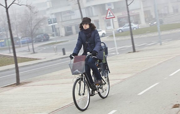 Una noia, abrigada, es passeja en bicicleta