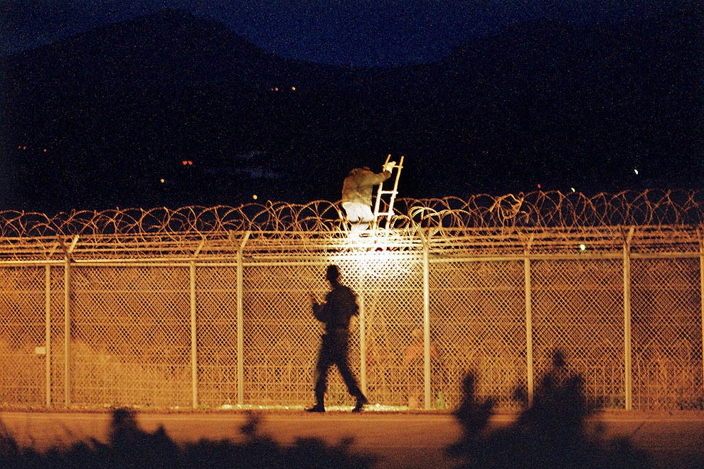 Un agent de la Guàrdia Civil intercepta un immigrant que intenta saltar la valla, l'any 2004.