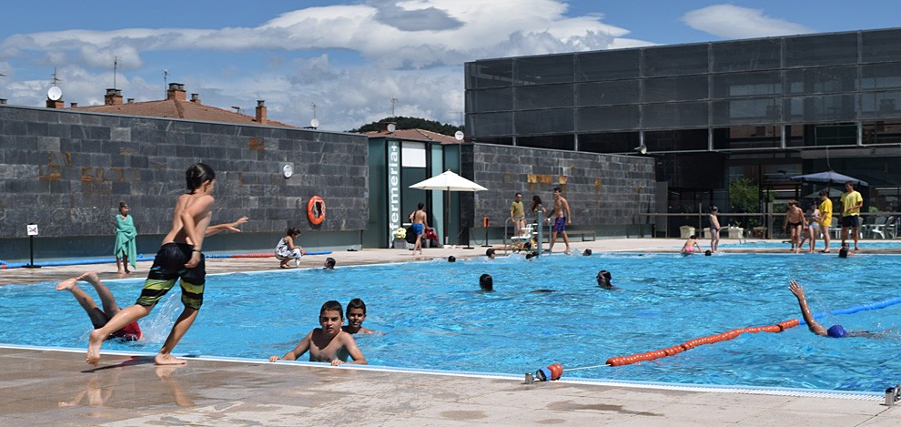 Uns joves es banyen a la piscina municipal d'Olot durant l'Estiu Riu.