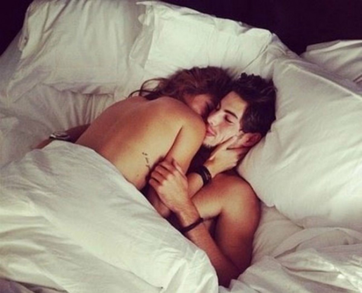 Муж и жена целуются на кровати
